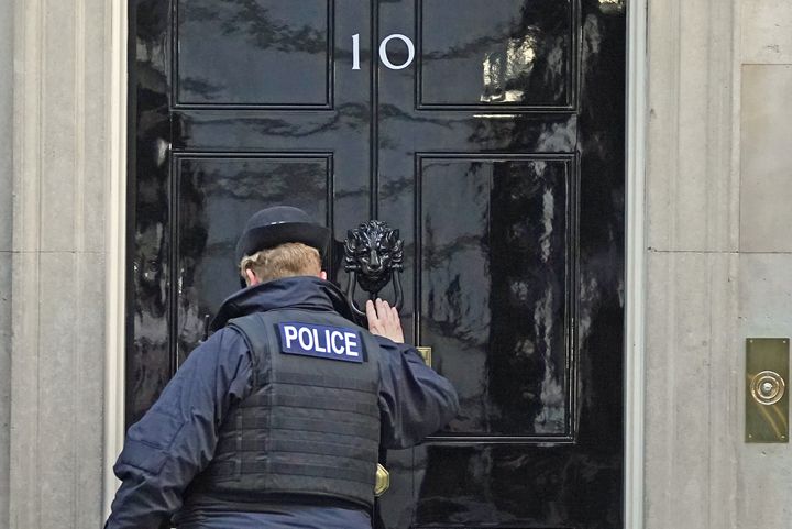 A police officer knocks on the door of the Prime Minister's official residence in Downing Street on Wednesday January 12, 2022.