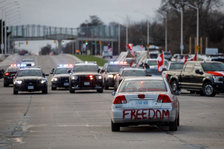 Police clear protestors and their vehicles from a blockade at the entrance to the Ambassador Bridge, that was sealing off the flow of commercial traffic over the bridge into Canada from Detroit, on February 12, 2022 in Windsor, Canada.