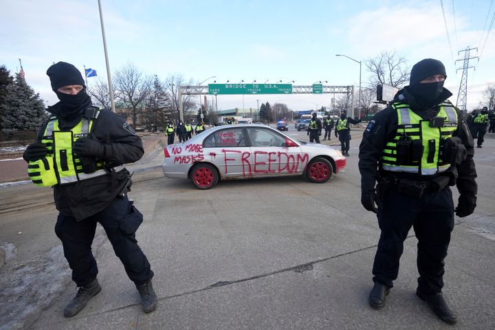 Police look on as a protest vehicle leaves a demonstration which blocked traffic across the Ambassador Bridge in Windsor, Ontario on Saturday, Feb. 12, 2022. (Nathan Denette/The Canadian Press via AP)