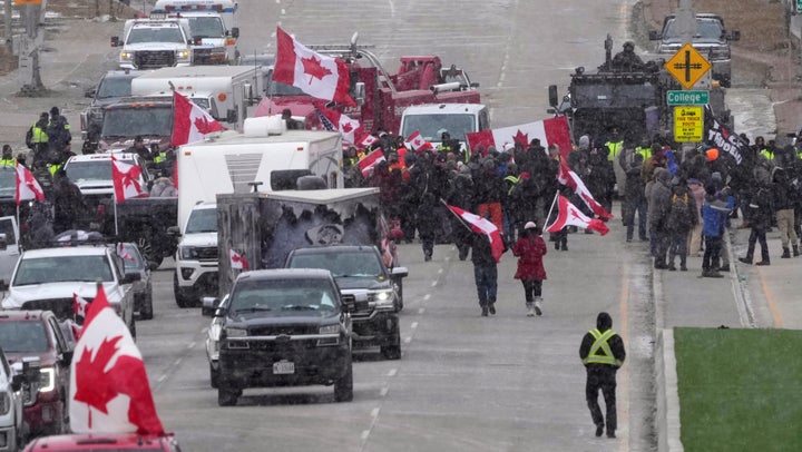 Protesters face police officers as they enforce an injunction against their demonstration, which has blocked traffic across the Ambassador Bridge by protesters against COVID-19 restrictions, in Windsor, Ont., Saturday, Feb. 12, 2022. (Nathan Denette /The Canadian Press via AP)