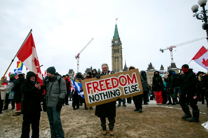 Don Stephens, 65, a retired graphic designer, holds a sign on Parliament Hill to support trucks lined up in protest of COVID-19 vaccine mandates and restrictions in Ottawa, Ontario, on Saturday, Feb. 12, 2022. (AP Photo/Ted Shaffrey)