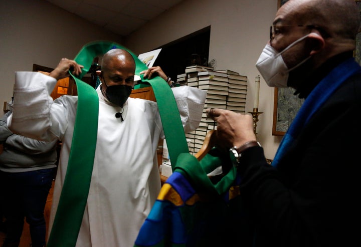 The Rev. Bryan Massingale, left, prepares for Mass with the help of sacristan Darren Johnson.