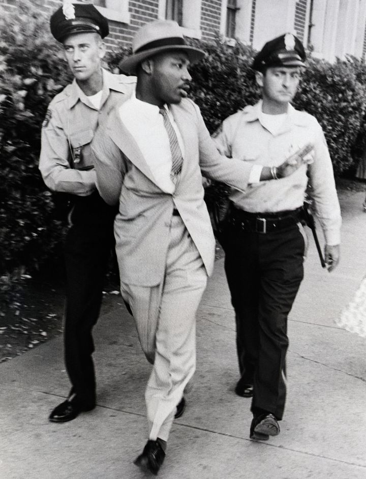 Police officers arrest Martin Luther King Jr. outside a courtroom where one of his integration lieutenants was on the stand. King charged that he was beaten and choked by the arresting officers. Police denied the charges.