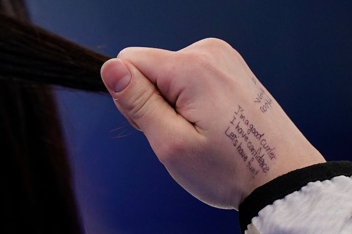 Japan's Satsuki Fujisawa runs her fingers through her hair and a message to herself written on her hand: "I'm a good curler. I have confidence. Let's have fun!"