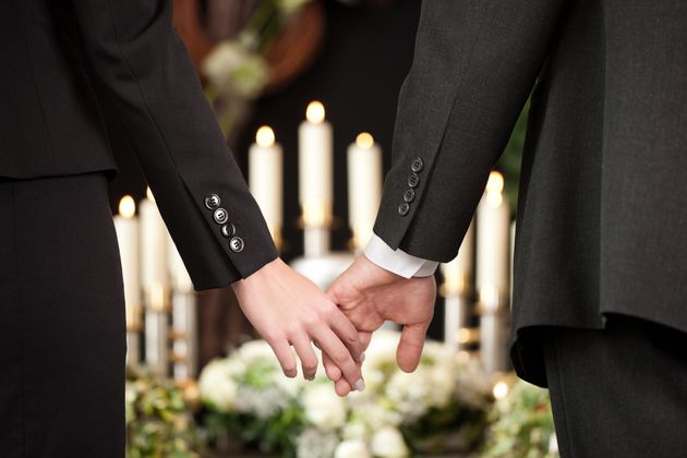 Un couple se tient la main à des funérailles. Image