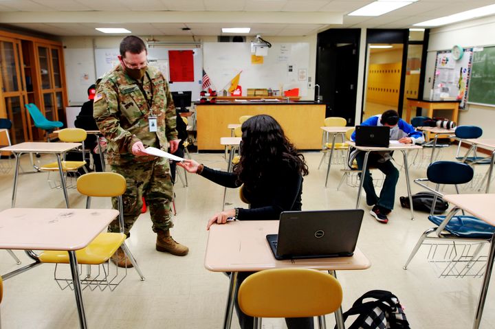 Substitute teacher and New Mexico Army National Guard specialist Michael Stockwell takes a geology assignment from Lilli Terrazas, 15, at Alamogordo High School, on Feb. 8, 2022, in Alamogordo, N.M. 