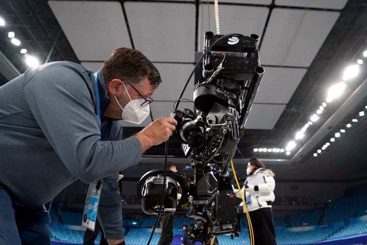 Ο φωτογράφος του Associated Press, David J. Phillip, στήνει μια ρομποτική κάμερα στο τουρνουά καλλιτεχνικού πατινάζ ενόψει των Χειμερινών Ολυμπιακών Αγώνων του 2022, Σάββατο 22 Ιανουαρίου 2022, στο Πεκίνο. (AP Photo/Chris Carlson)