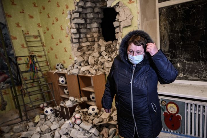 A woman stands among debris after the shelling of a kindergarten in the settlement of Stanytsia Luhanska, Ukraine, on February 17, 2022. (Photo by Aris Messinis/AFP via Getty Images)