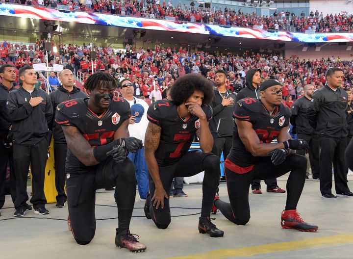 2016年、NFLのスター選手だったコリン・キャパニック氏（中央）らが人種差別と黒人に対する警察官の暴力に抗議するため、試合前の国歌斉唱中にひざまずく抗議のアクション。キャパニック氏は2017に自由契約選手になった後、どのチームからも契約をオファーされなかった。