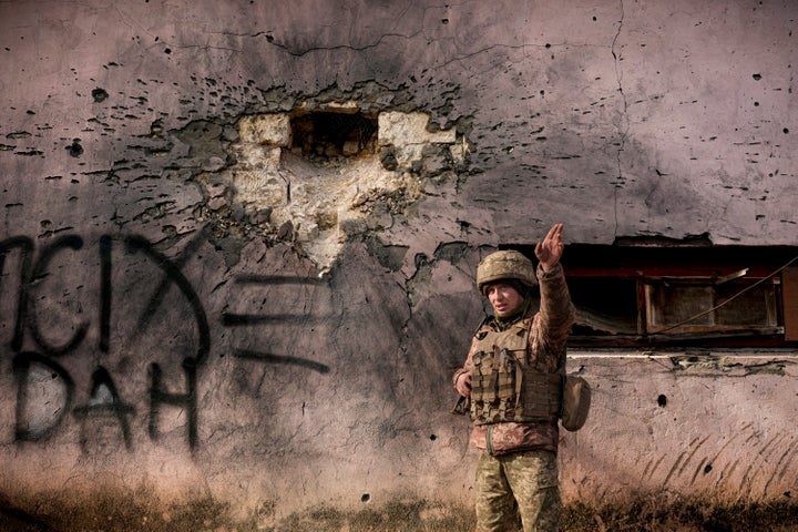 A Ukrainian serviceman points to the direction of the incoming shelling next to a building which was hit by a large caliber mortar shell in the frontline village of Krymske, Luhansk region, in eastern Ukraine on Saturday.