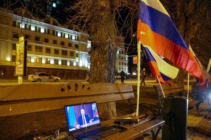Russian President Vladimir Putin is seen on a computer screen while addressing the nation in the Kremlin in Moscow, as people celebrate in the center of Donetsk, the territory controlled by pro-Russian militants, eastern Ukraine, late Monday, Feb. 21, 2022. In a fast-moving political theater, Russian President Vladimir Putin has moved quickly to recognize the independence of separatist regions in eastern Ukraine in a show of defiance against the West amid fears of Russian invasion in Ukraine. (AP Photo/Alexei Alexandrov)