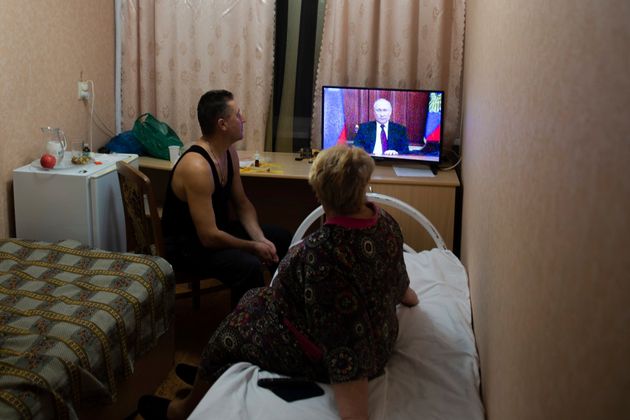 Des habitants évacués des territoires séparatistes en Ukraine regardent le discours...