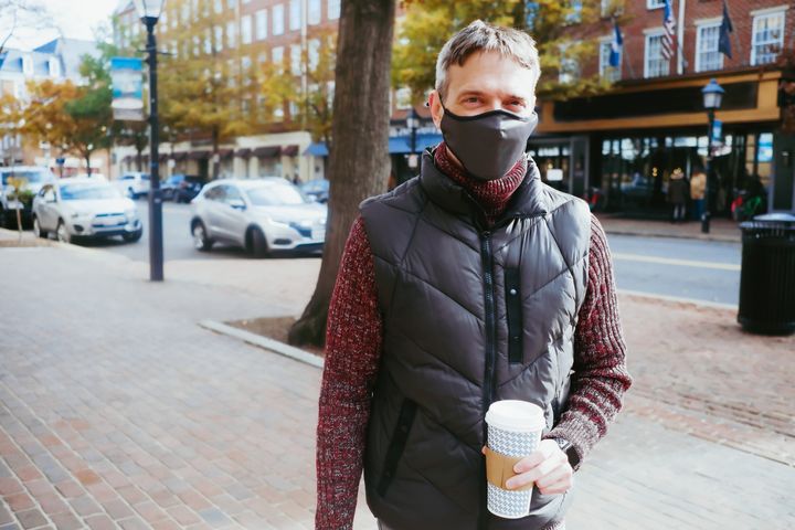 Close-up of mid adult white male in downtown district holding cup of coffee