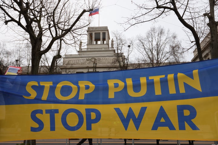 Des manifestants tiennent une banderole indiquant que Poutine arrête la guerre alors que des groupes de jeunes protestent contre l'intervention de l'Ukraine avec une chaîne humaine devant l'ambassade de Russie le 22 février 2022 à Berlin, en Allemagne.