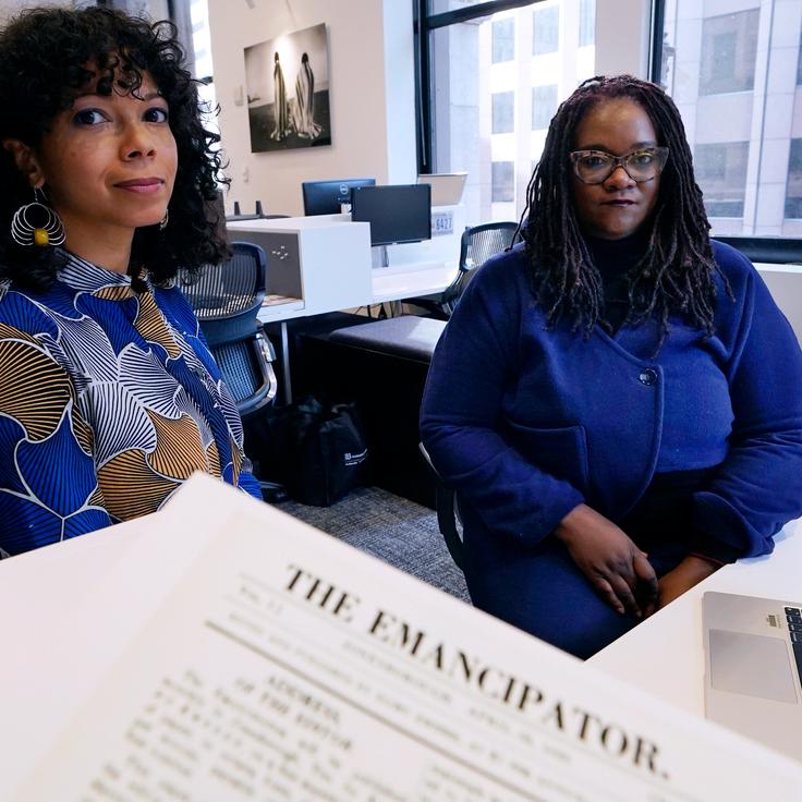Amber Payne, left, and Deborah Douglas co-editors-in-chief of the new online publication of "The Emancipator" pose at their office inside the Boston Globe, Wednesday, Feb. 2, 2022, in Boston. Boston University's Center for Antiracist Research and The Boston Globe's Opinion team are collaborating to resurrect and reimagine The Emancipator, the first abolitionist newspaper in the United States, which was founded more than 200 years ago.