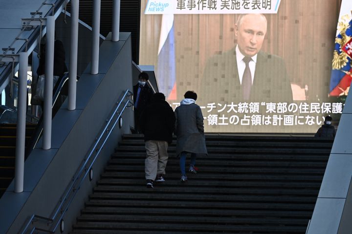Πολίτες περπατούν βλέποντας σε γιγαντοοθόνη το έκτακτο διάγγελμα του Βλαντιμίρ Πούτιν. 