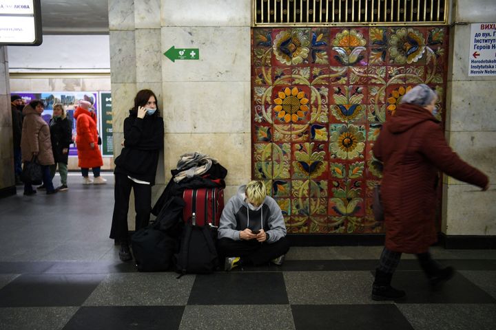 Ένα νεαρό ζευγάρι με μια βαλίτσα και τσάντες περιμένει σε σταθμό του μετρό στο Κίεβο.