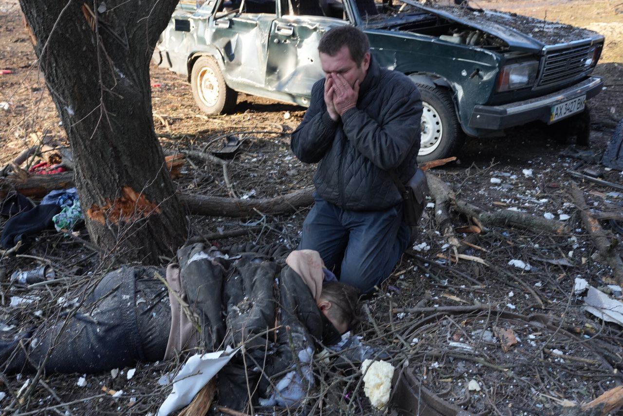 A man mourns near a body following an airstrike on an apartment complex outside of Kharkiv.