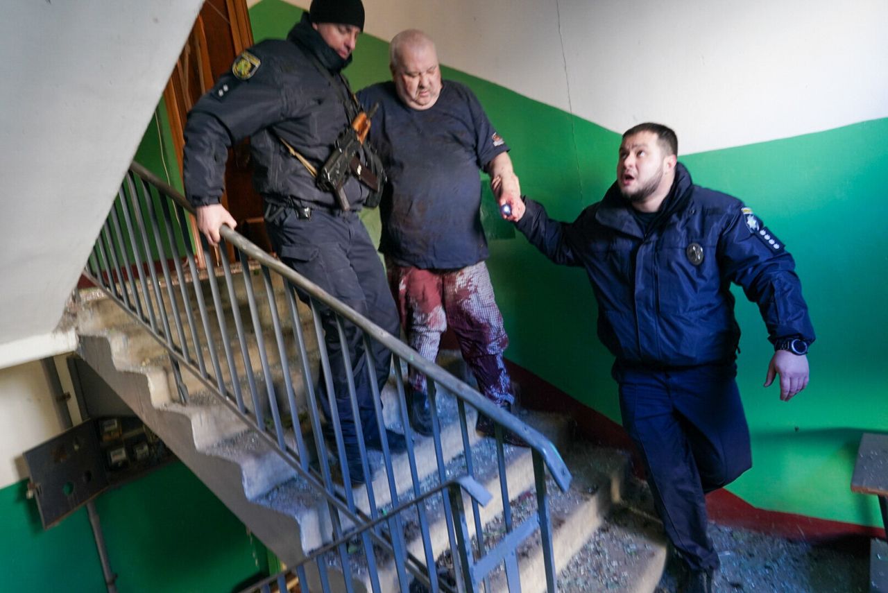 Ukrainian security forces accompany a wounded man after an airstrike hit an apartment complex in Kharkiv Oblast.