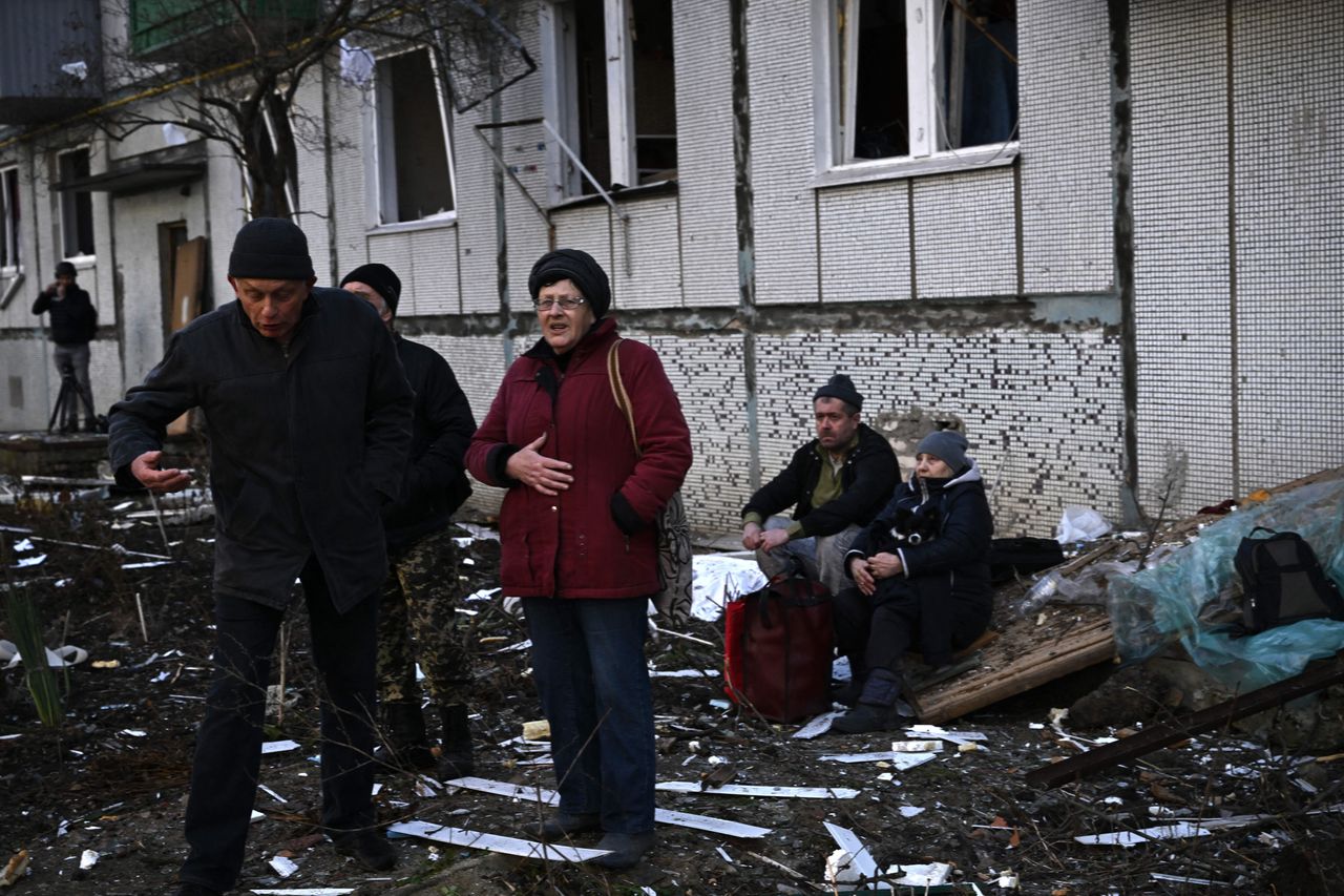 People outside a destroyed building, following bombings of the eastern Ukrainian town of Chuguiv.