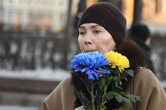 ウクライナの旗の色である青と黄の花を持って、モスクワの抗議デモに参加した人（2022年2月24日）