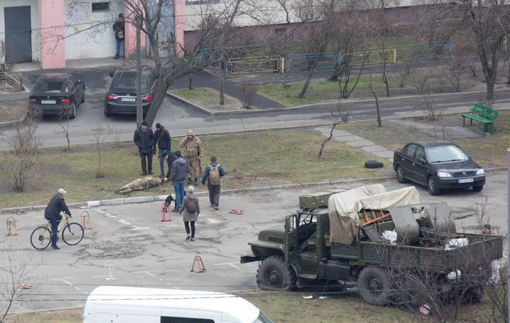 Πολίτες και ένας Ουκρανός στρατιώτης στέκονται πάνω από νεκρό άνδρα με στρατιωτική στολή, δίπλα σε στρατιωτικό όχημα που δεν φέρει διακριτικά στην περιοχή του Κιέβου. Το ίδιο φορτηγό, στο ίδιο σημείο, εικονίζεται σε βίντεο στο Twitter που έχει αναρτηθεί από ιδώτες, οι οποίοι υποστηρίζουν ότι το περιστατικό συνέβη στην περιοχή Obolon στα βόρεια της Ουκρανικής πρωτεύουσας και ότι Ουκρανοί στρατιώτες σκότωσαν Ρώσους στρατιώτες. REUTERS/Olga Yakimovich