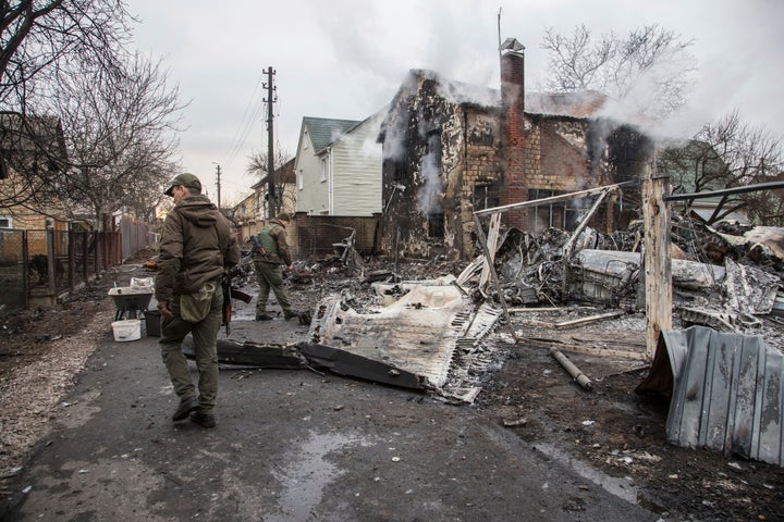 Ukrainian servicemen investigate the fragments of a downed aircraft seen in in Kyiv, Ukraine, Friday, Feb. 25, 2022. It was unclear what aicraft crashed and what brought it down amid the Russian invasion in Ukraine.