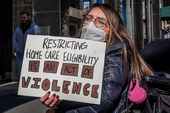A participant in a wheelchair holds a sign at a Feb. 9 protest by Downstate New York ADAPT outside the New York City Council offices in Manhattan. Disabled activists and their supporters across New York criticized the state's refusal to repeal restrictions on home care access amid the pandemic.