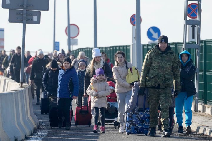 A Polish border guard assists refugees from Ukraine as they arrive in Poland.