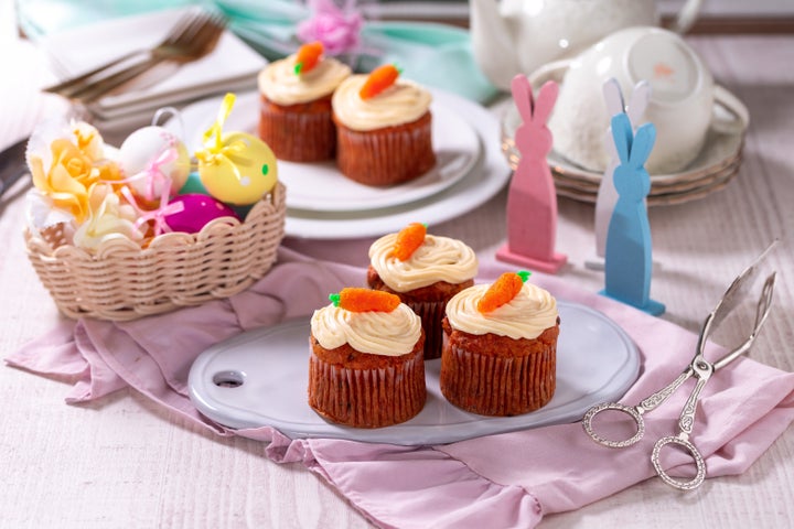 Carrot cake muffins with cream cheese, topped with marzipan carrots on a plate. Delicious homemade dessert.