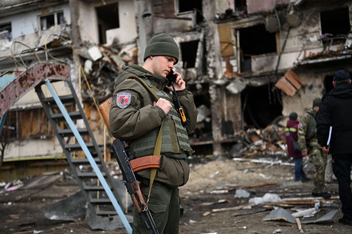 A Ukrainian serviceman in front of a damaged residential building at Koshytsa Street, a suburb in the capital Kyiv.
