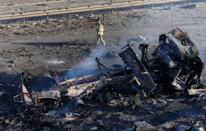 A Ukrainian soldier walks past debris of a burning military truck, on a street in Kyiv, Ukraine, Saturday, Feb. 26, 2022. (AP Photo/Efrem Lukatsky)