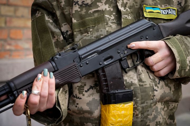 An armed civil defense woman holds a Kalashnikov assault rifle while patrolling an empty street due to a curfew in Kyiv, Ukraine, Sunday, Feb. 27, 2022. (AP Photo/Efrem Lukatsky)
