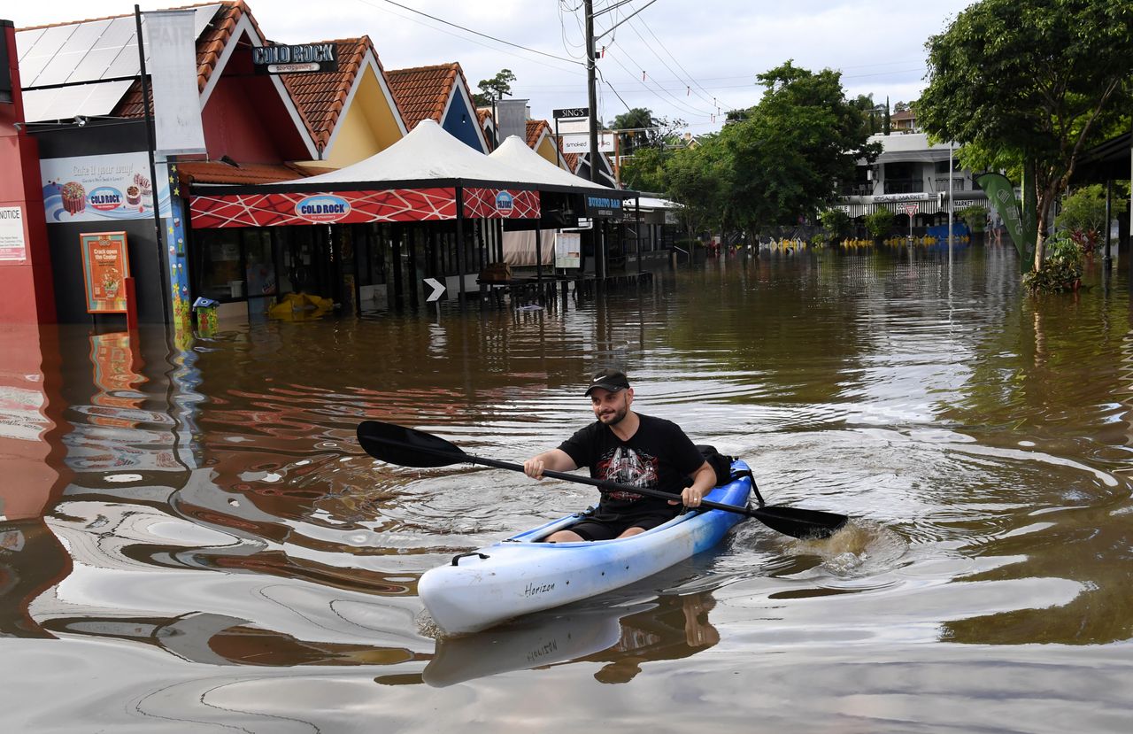 A man paddles a kayak on a flooded street in Brisbane, Australia, on Monday.