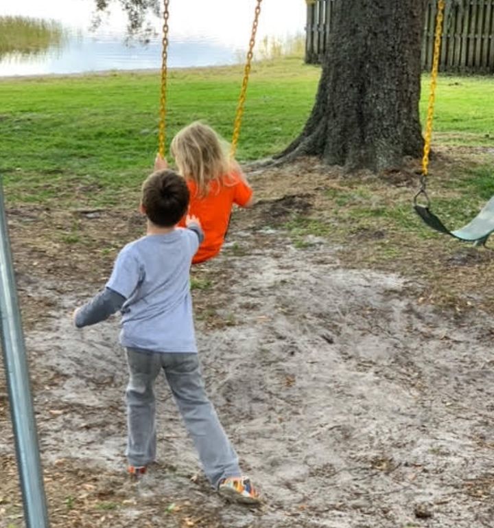 Maxim pushes his sister on a swing. "He stepped into the role of 'big brother' naturally," his mother says.