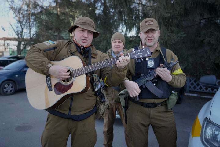 Members of the Ukrainian civil defense, one mimicking a guitar with his assault rifle, play a song while waiting to escort a fuel transport in Kyiv, Ukraine, Monday, Feb. 28, 2022. Explosions and gunfire that have disrupted life since the invasion began last week appeared to subside around Kyiv overnight, as Ukrainian and Russian delegations met Monday on Ukraine's border with Belarus.