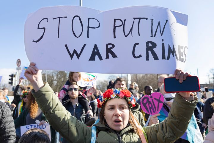 A demonstrator holds a sign that reads "Stop Putin's war crimes" while protesting Russia's massive military operation against Ukraine during a rally on the place of the United Nations in Geneva, Switzerland, Saturday, February 26, 2022. (Salvatore Di Nolfi/Keystone via AP)