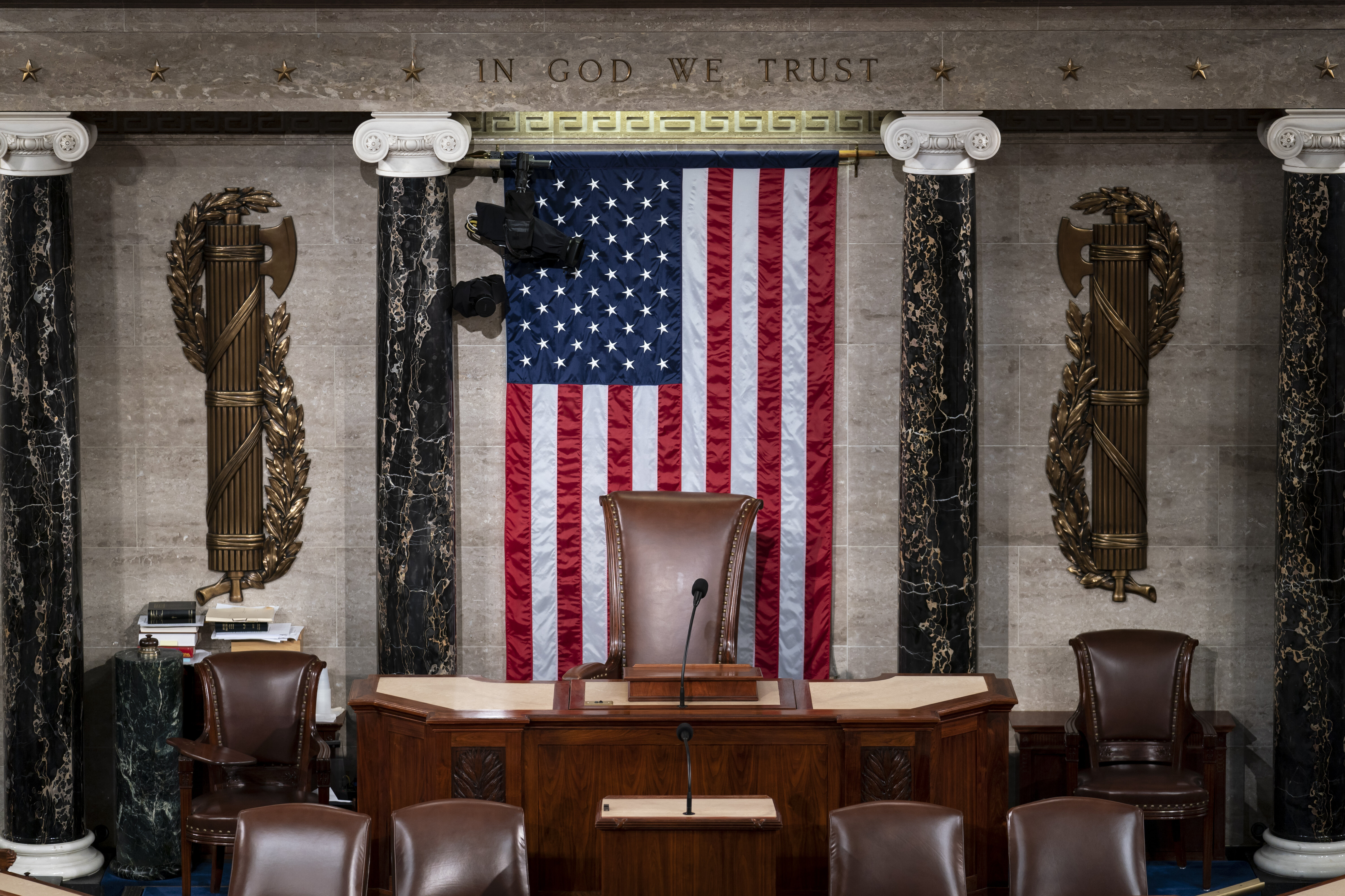 The speaker's dais in the House of Representatives with American flag hanging up behind chair.