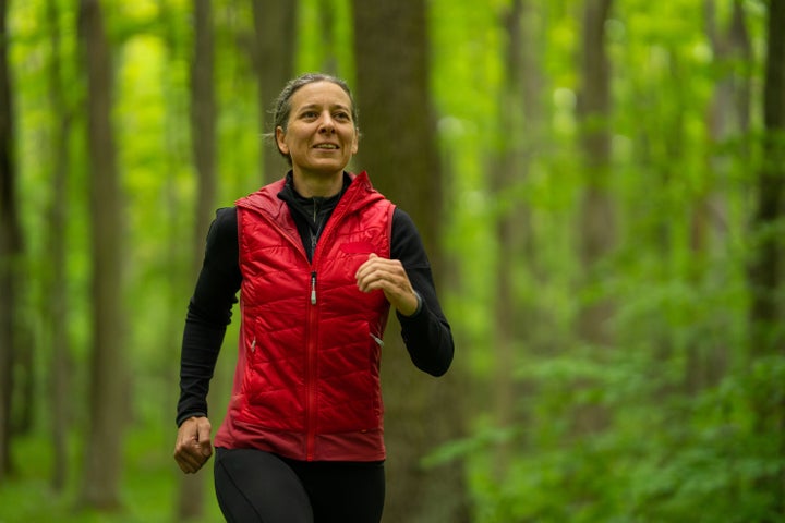 Female Runner in Park With Blurred Trees in Background, Waist Up