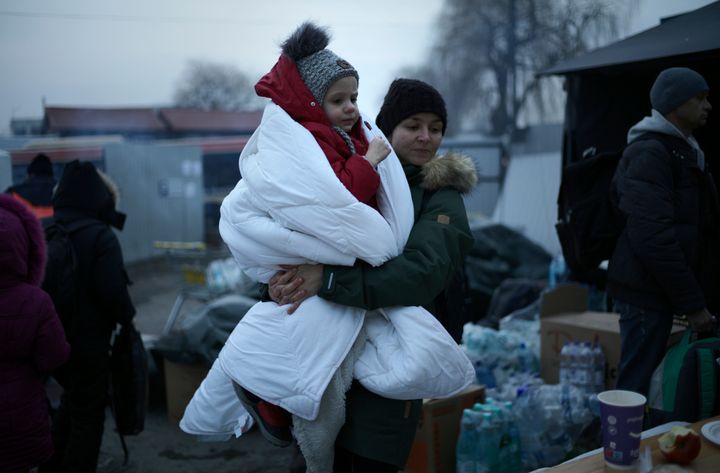 A woman walks with a child wrapped in a blanket as she waits at a refugee crossing in Medyka, Poland on Thursday. (AP Photo/)