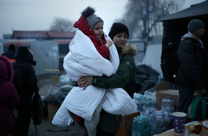 A woman walks with a child wrapped in a blanket as she waits at a refugee crossing in Medyka, Poland on Thursday. (AP Photo/)