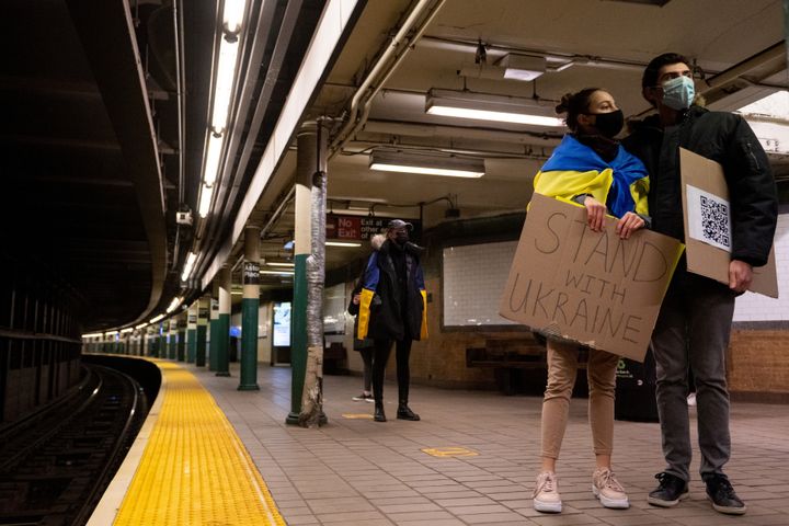 People holding signs wait for the subway before attending a "Stand With Ukraine" rally at the Russian Consulate on Feb. 27 in New York City.