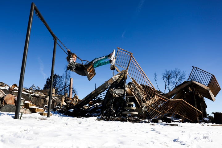 Charley Ferrera, 8, plays on a swing at what remains of her grandfather's house in a neighborhood decimated by the Jan. 2 Marshall Fire in Louisville, Colorado. Scientists say the blaze, which may be Colorado's costliest wildfire in history, is a sign of worse to come as policymakers fail to transition the U.S. away from fossil fuels.