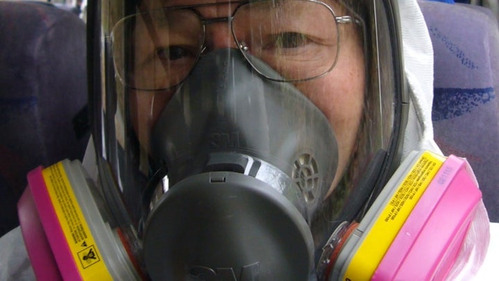 Umematsu wearing a mask and white protective clothes in the bus heading to the site.