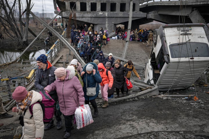 People cross on an improvised path under a bridge that was destroyed by a Russian airstrike, while fleeing the town of Irpin, Ukraine, Saturday, March 5, 2022. (AP Photo/Vadim Ghirda)