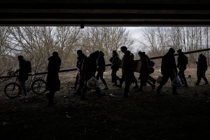 People cross on an improvised path under a bridge that was destroyed by a Russian airstrike, while fleeing the town of Irpin, Ukraine, Saturday, March 5, 2022. (AP Photo/Vadim Ghirda)