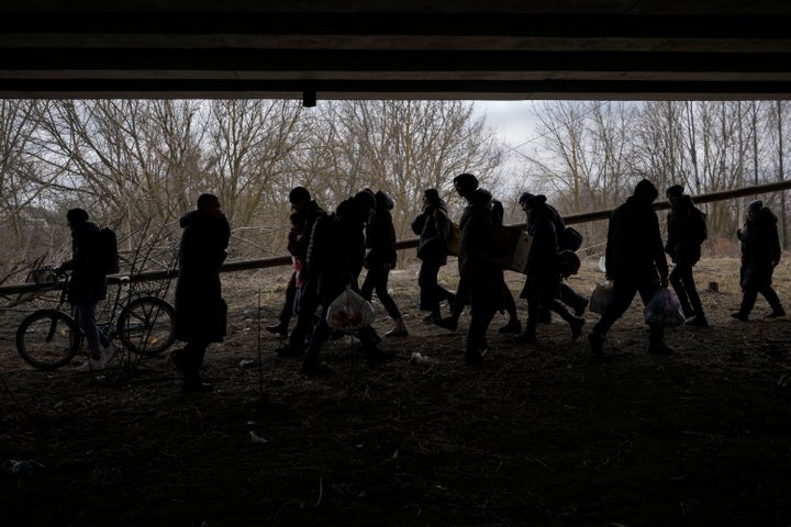 People cross on an improvised path under a bridge that was destroyed by a Russian airstrike, while fleeing the town of Irpin, Ukraine, Saturday, March 5, 2022. (AP Photo/Vadim Ghirda)