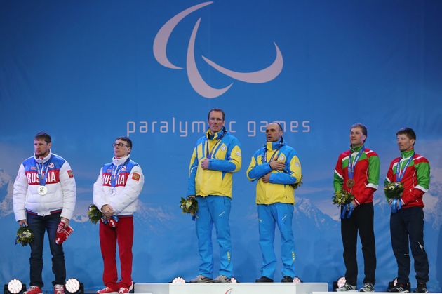 表彰台でメダルを隠すバイアスロンの選手（中央）