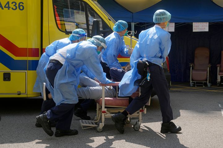 Medical workers move an elderly patient to a hospital in Hong Kong on Friday. The city, which is seeing deaths soar, is testing its entire population of 7.5 million three times this month.
