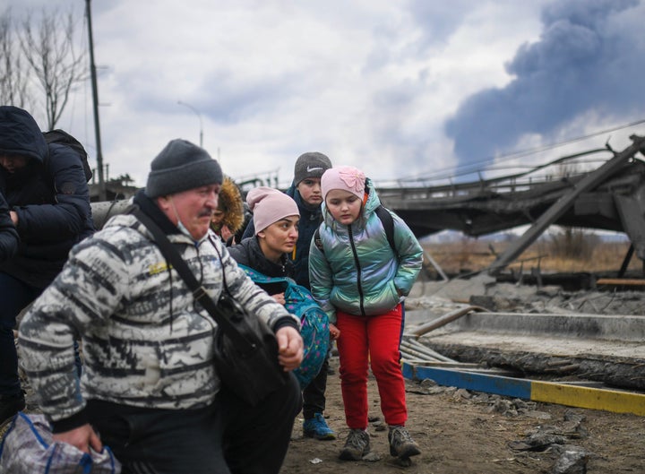 Ukrainian soldiers help people trying to leave the city amid the collapsed structures and debris on Mar. 6, 2022, in Irpin, Ukraine.